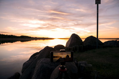 Reflection of photographing on beach against sky during sunset
