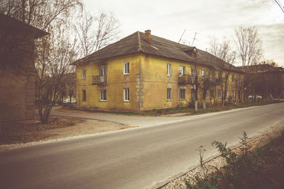 Empty road by buildings against sky