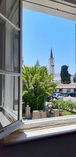 Plants and trees by building against clear sky