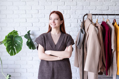 Portrait of young woman standing against wall