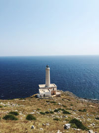 Lighthouse by sea against clear sky