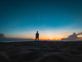 Silhouette woman walking at beach against clear sky during sunset