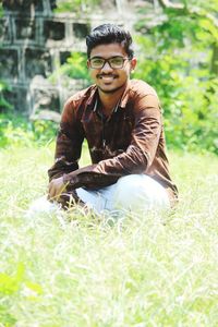 Portrait of young man sitting on field