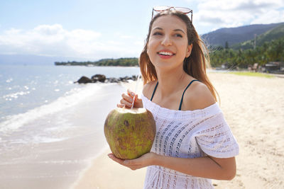 Woman drinking green coconut water on the tropical beach