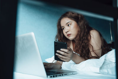 Young woman using laptop while lying on sofa at home