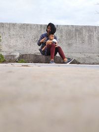 Full length of woman sitting on wall