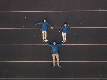 Optical illusion of father carrying sons on hands against road