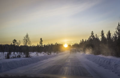 Snow covered trees against sky during sunset