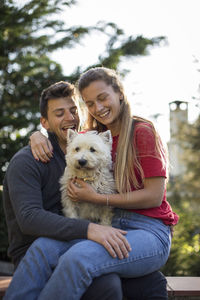 Portrait of happy woman with dog sitting outdoors