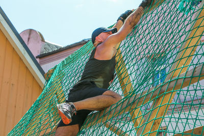 Low angle view of man holding rope against sky