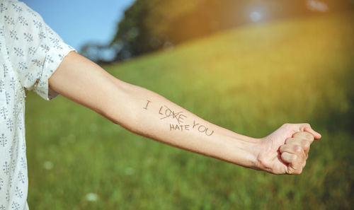 Cropped hand of man showing text written on forearm at park