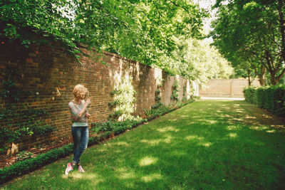 Full length of woman standing by retaining wall at park