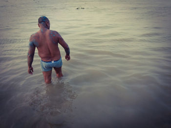 Full length of shirtless man standing in sea