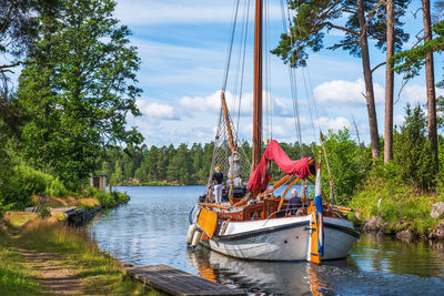 Sailboats moored in river against sky