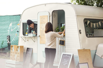 Male owner looking at female colleague working outside food truck