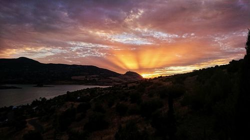 Scenic view of sea against dramatic sky during sunset