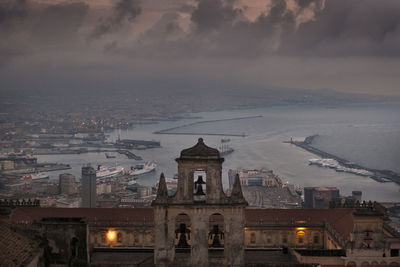 Illuminated buildings in city against sky at sunset