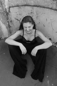 High angle view of woman laughing while sitting on floor against wall