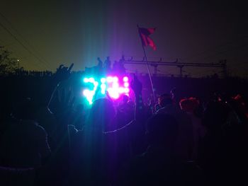 Crowd at music concert against sky at night