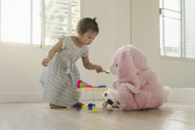 Cute girl playing with toy on floor at home