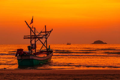 Fishing boat in sea against orange sky