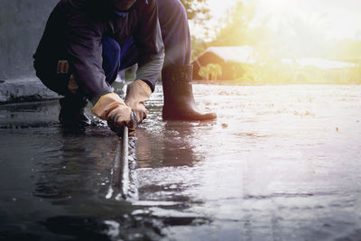 Low section of man standing on wet shore