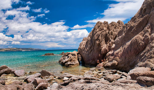 Rocks on shore by sea against sky