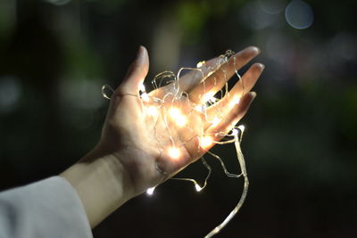 Close-up of hand holding illuminated string lights
