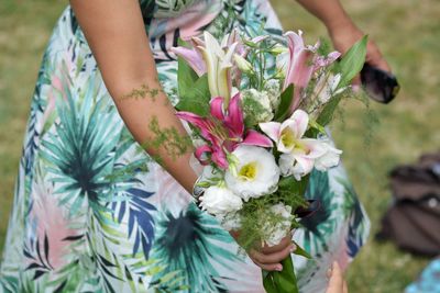 Low section of woman holding bouquet