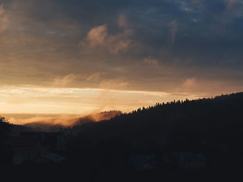 Silhouette of trees against dramatic sky