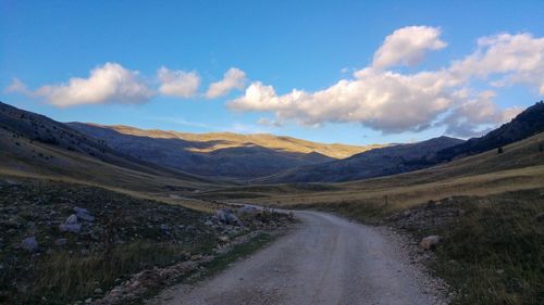 Scenic view of road by mountains against sky