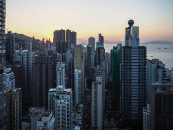 Modern buildings in city against sky during sunset