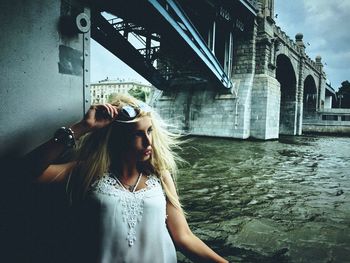 Beautiful woman standing against bridge over river