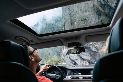 Man driving car against rock formations