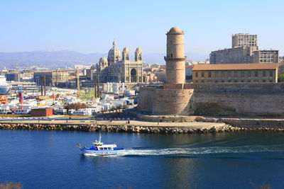 Boats in sea against buildings in city