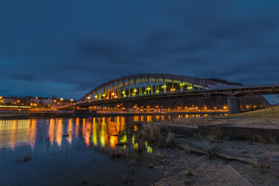 Illuminated bridge over river against sky at night