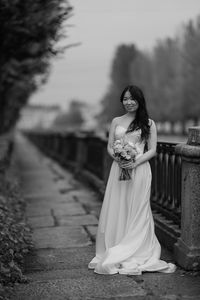 Side view of young woman standing against sky