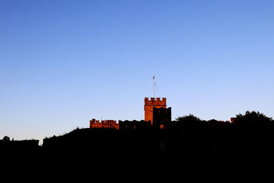 Low angle view of silhouette building against clear sky