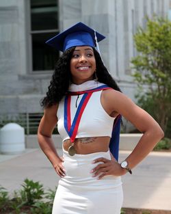 Woman in mortarboard standing against building