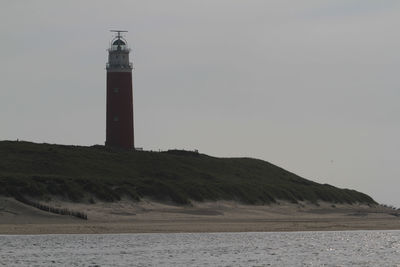 Lighthouse by sea against clear sky