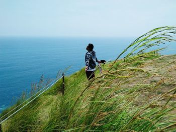 Man standing on mountain by sea against sky