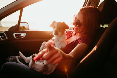 Woman with dog sitting in car