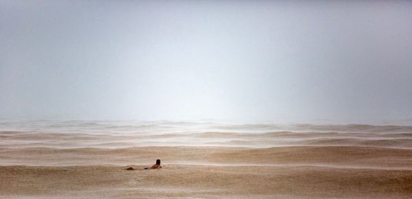 People standing on beach against clear sky