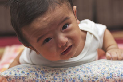 Close-up portrait of cute baby boy lying on bed at home