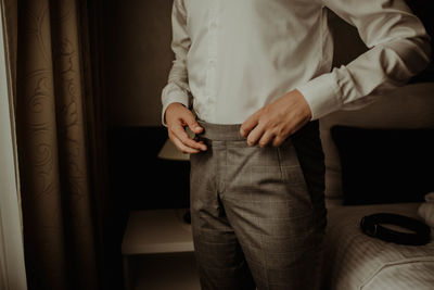 Midsection of man getting dressed while standing at home