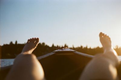 Low section of man lying against clear sky