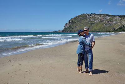 Friends on shore at beach against sky