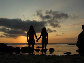 Silhouette people on beach against sky during sunset