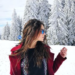 Young woman wearing sunglasses while standing in snow covered forest