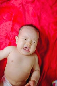 High angle view of baby girl crying while lying on bed